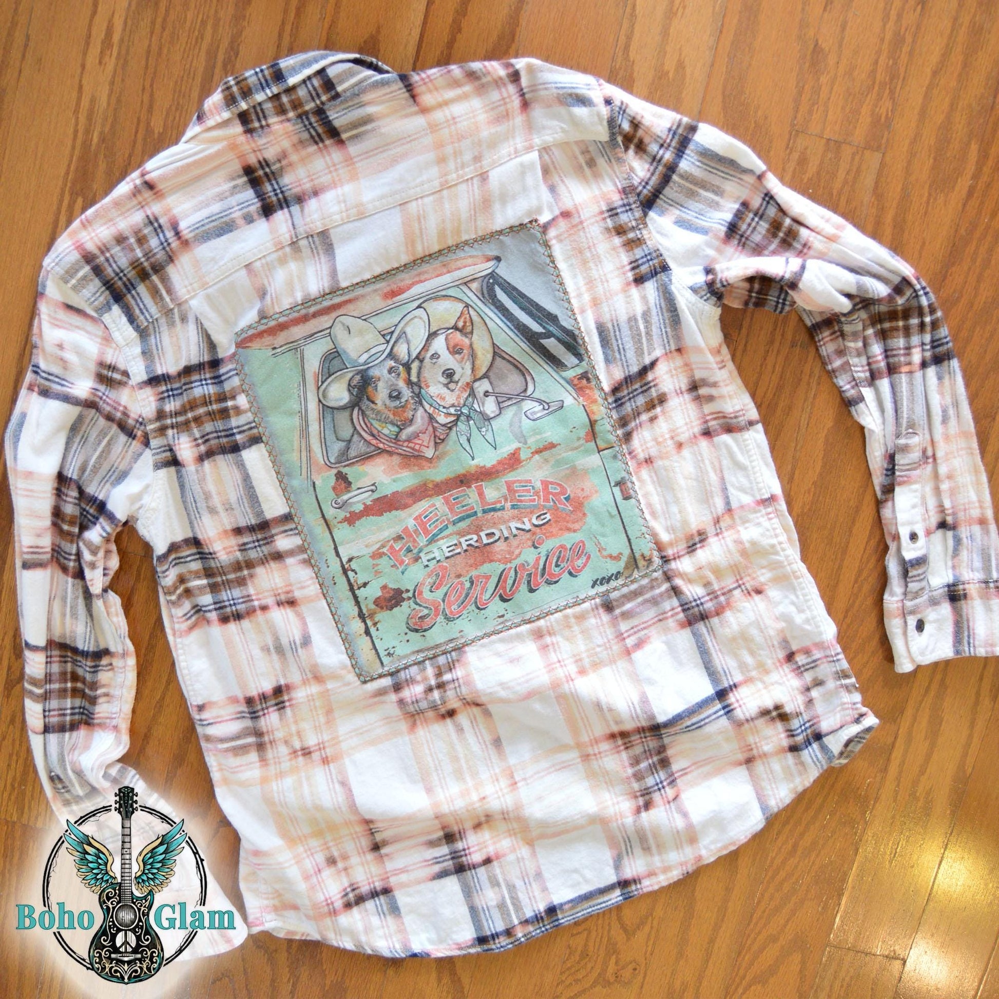 Flat Lay Back: The shirt laid flat on a wood floor to showcase the full scale of the herding service graphic and the stitching detail.