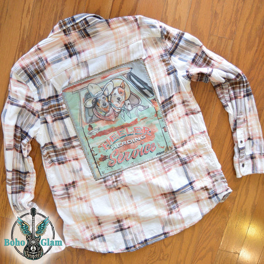 Flat Lay Back: The shirt laid flat on a wood floor to showcase the full scale of the herding service graphic and the stitching detail.
