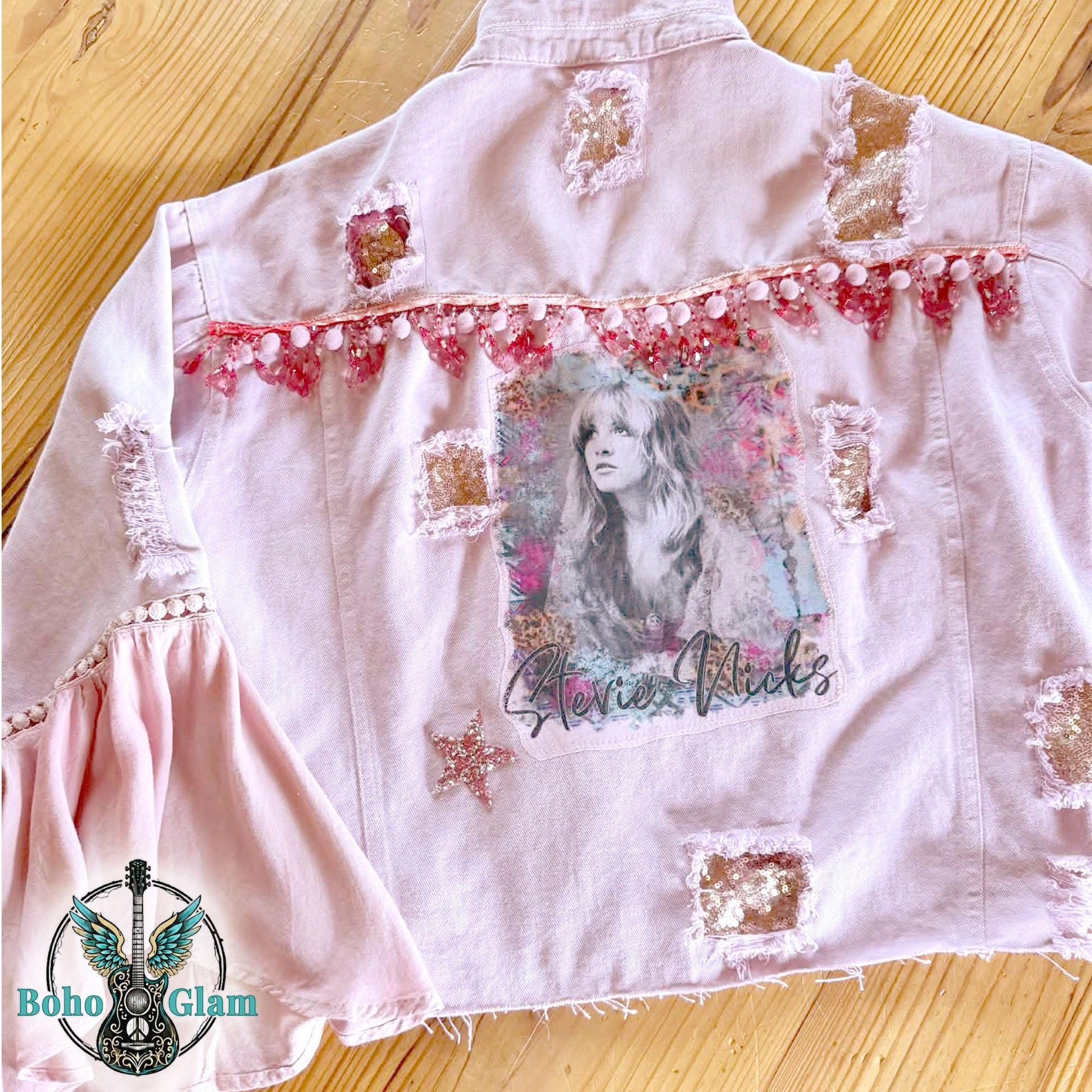 Back detail of pink upcycled denim jacket with watercolor graphic, pom trim, distressed patches and sequin accents, one of a kind Stevie Nicks inspired jacket
