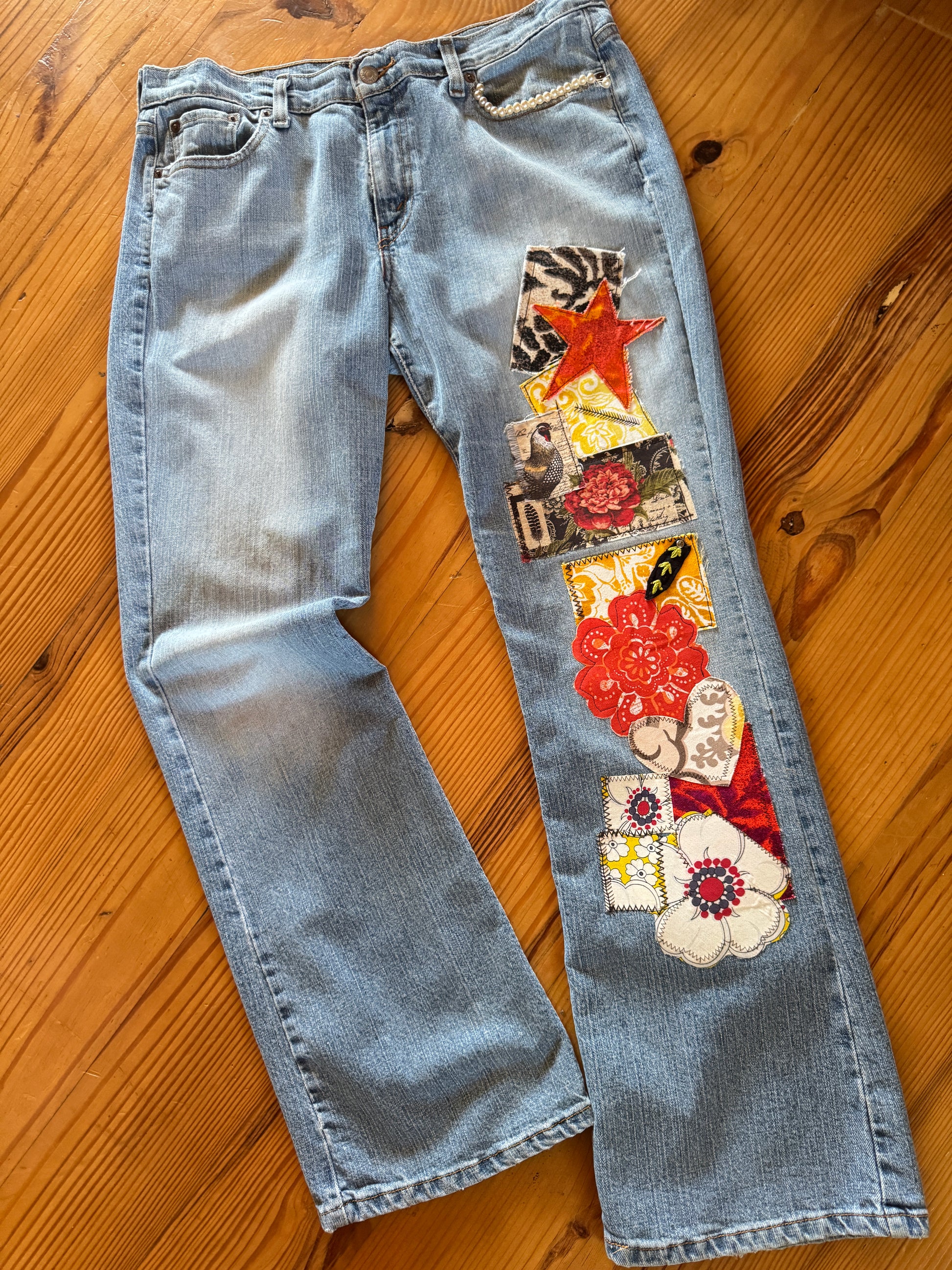 A pair of upcycled Levi flare jeans with a patchwork design featuring animal prints, florals, and a burnt orange star.